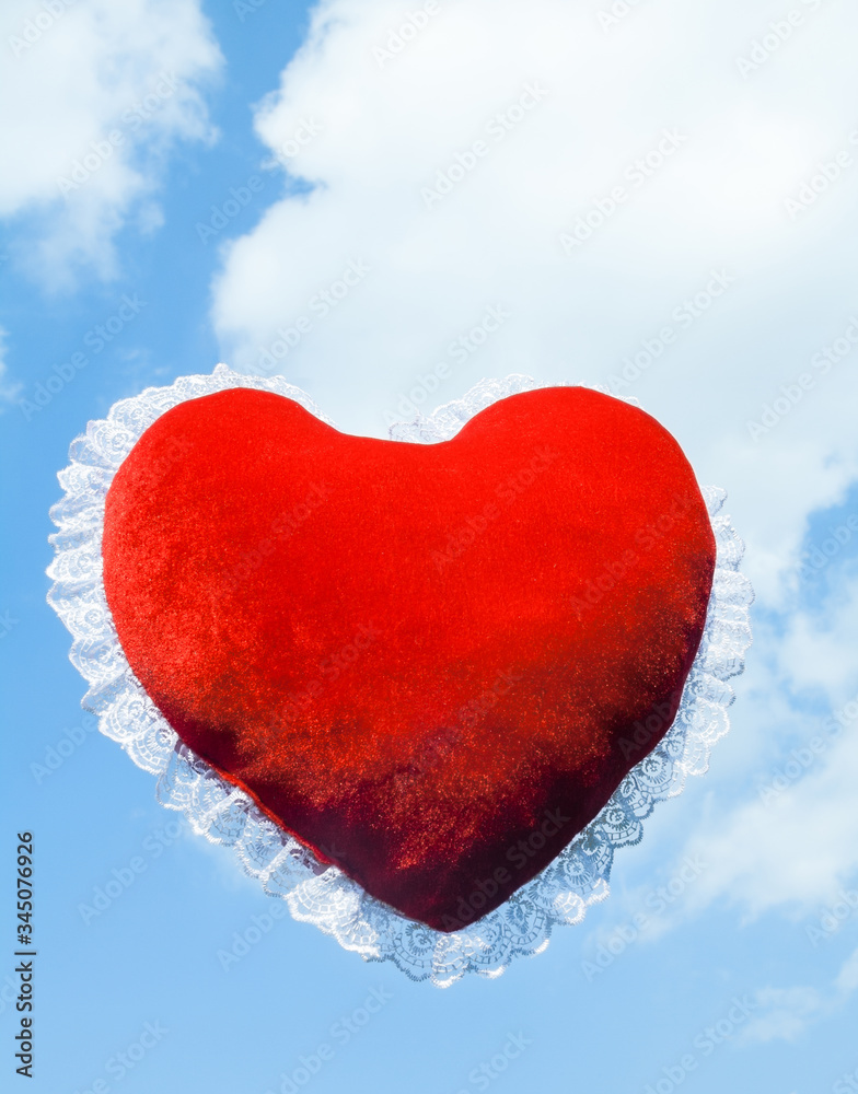 Red heart shaped cushion against the sky Red heart shaped cushion against the sky