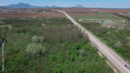Aerial view above cars driving along empty countryside road on sunny day