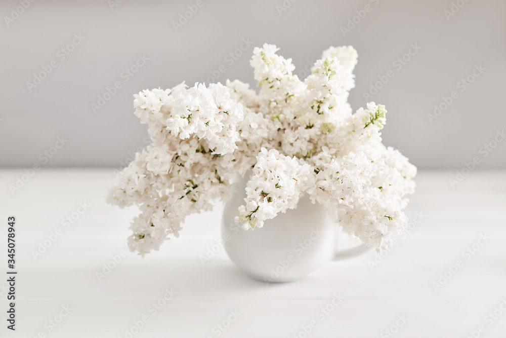 Bouquet of white lilac in vase on table in kitchen. Happy birthday greeting card. Hello spring and summer. Greeting card for Women's Day and Mother's Day. Spring season, copy space