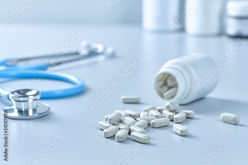 Closeup of a stethoscope and many medicinal capsules or tablets