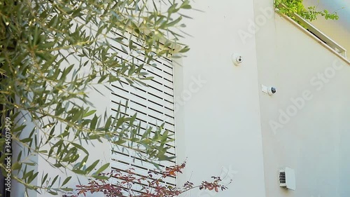Cinemagraph of an electric rolling shutter opening on a window. An outdoor smart home professional security cameras system. Loop wide shot with a low angle.
