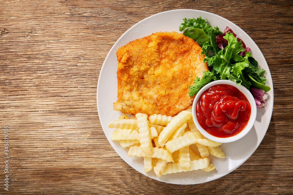 plate of fried breaded chicken meat or Schnitzel with french fries and salad plate of fried breaded chicken meat or Schnitzel with french fries and salad