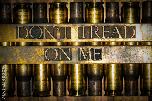 Photo of real authentic typeset letters forming Dont Tread On Me text on vintage textured grunge copper background over layer of 50 caliber bullet casings