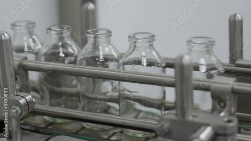 glass bottles on medical solution conveyor line close up medical industry