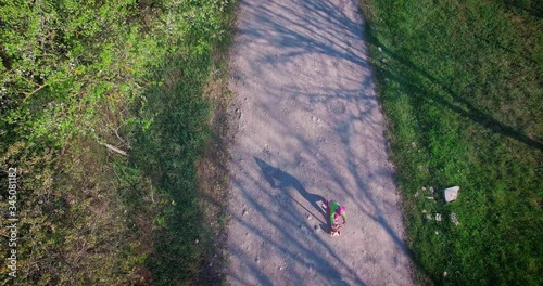 Little kid ride a scooter in a village on a spring day, video from a drone