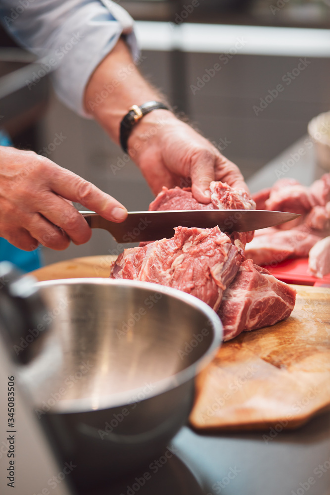 The chef cuts a meat with a knife.