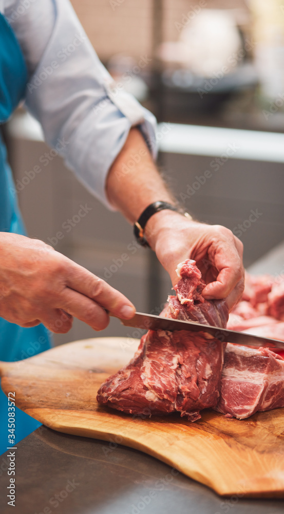 The chef cuts a meat with a knife.