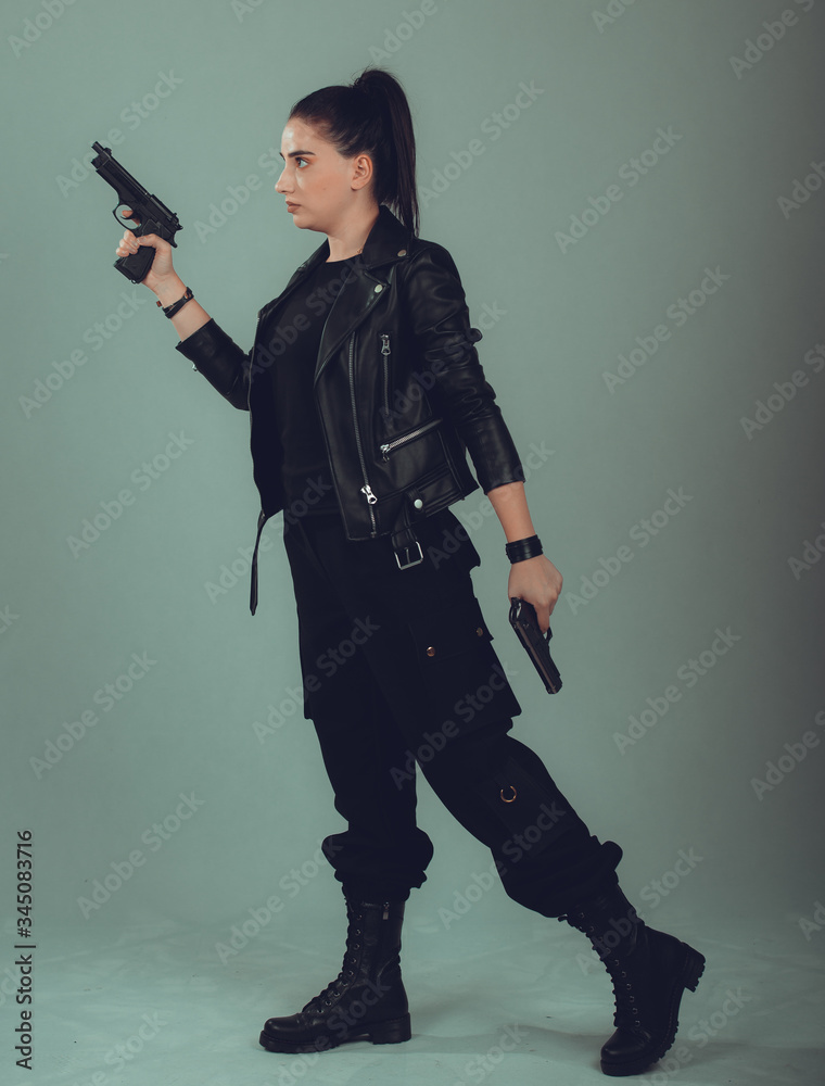Shot of a sexy military woman posing with guns,in a black jacket Shot of a sexy military woman posing with guns,in a black jacket