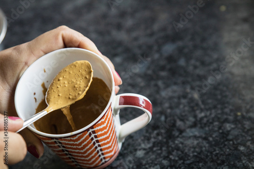 Valokuva a girl making hand beaten coffee or indian cappuccino in a mug with a spoon