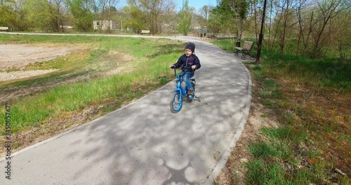 child of preschool age riding her bike with extra wheels on the side