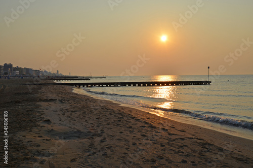 Beautiful coastline of the Adriatic Sea. Sunset on the beach of Lido di Jesolo. Piers in the sea