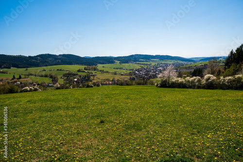 beautiful spring meadows in the mountains with a village in the valley  czech 