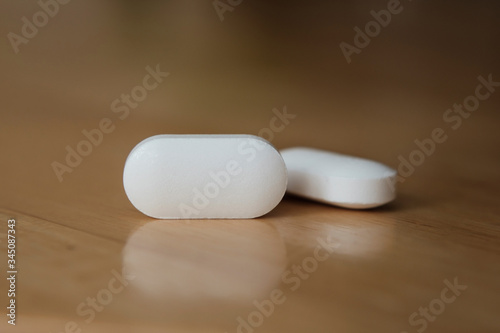 Pill on top reflective wooden surface. Illustrative for profit from pharmaceutical industry, cost of pills and medical care. Empty space avalible for inserting name of the drug. Concept photo.