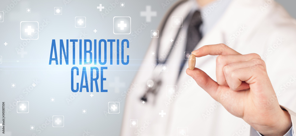 Close-up of a doctor giving a pill with ANTIBIOTIC CARE inscription, medical concept Close-up of a doctor giving a pill with ANTIBIOTIC CARE inscription, medical concept