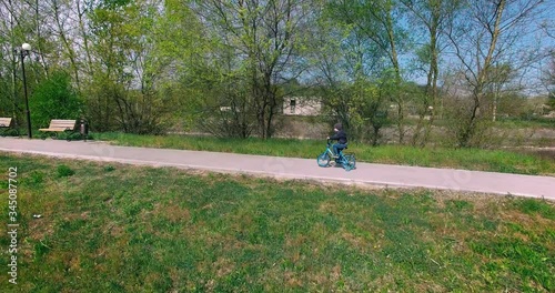 little boy riding on a blue bike in the Park,a video with a quadcopter