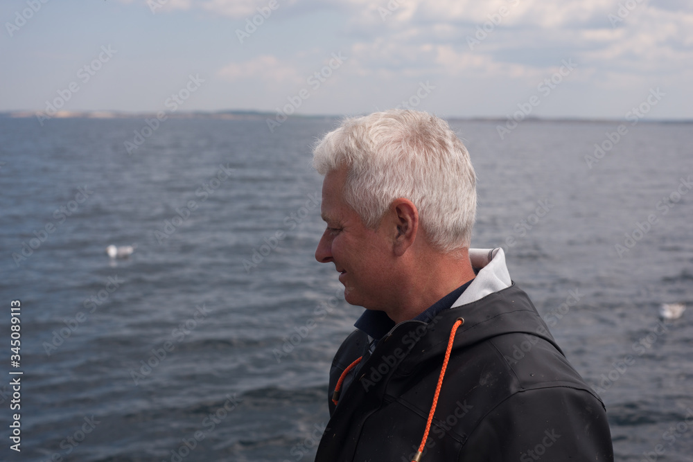 Fototapeta premium Portrait of a fisherman in a rain jacket on a boat