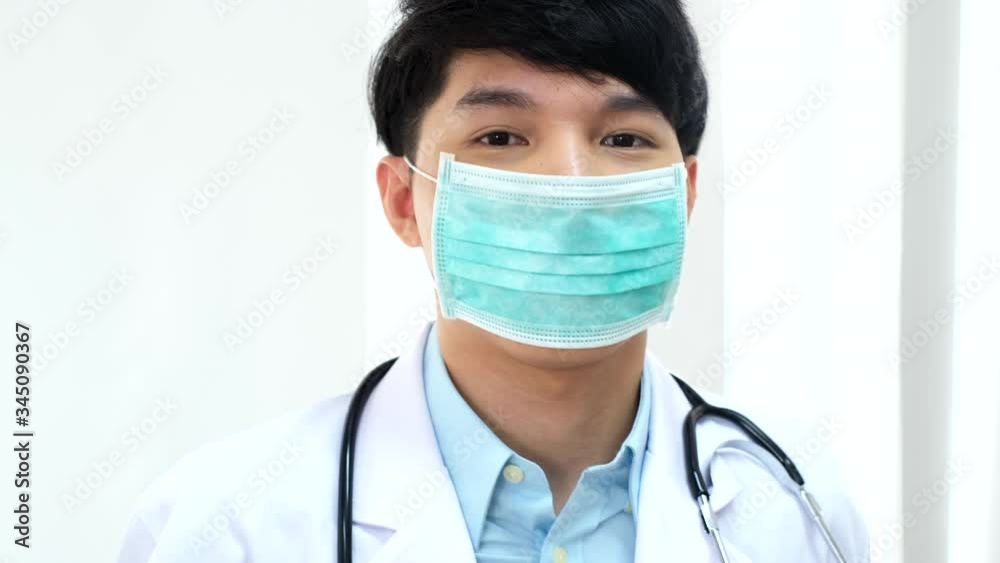 Young Asian Doctor putting on protective mask at clinic.the concept health and safety, N1H1 coronavirus quarantine, virus protection..takes off the face mask. Young Asian Doctor putting on protective mask at clinic.the concept health and safety, N1H1 coronavirus quarantine, virus protection..takes off the face mask.