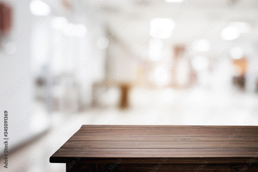 Empty wooden desk space and blurry background of white bokeh light department store for product display montage. Empty wooden desk space and blurry background of white bokeh light department store for product display montage.