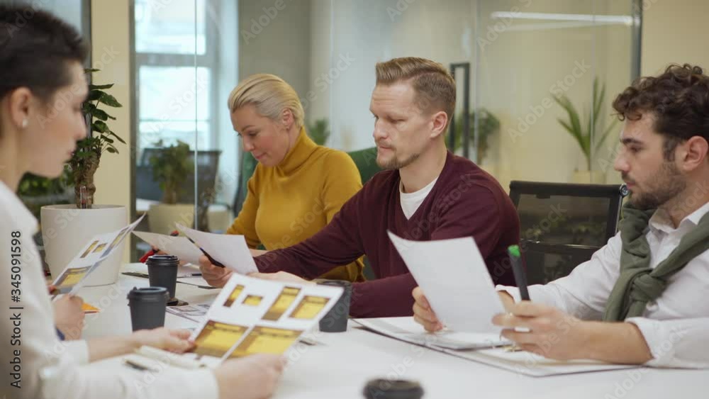 Tilt down tracking shot of middle aged manager explaining ideas while brainstorming with colleagues sitting at table in team meeting Tilt down tracking shot of middle aged manager explaining ideas while brainstorming with colleagues sitting at table in team meeting