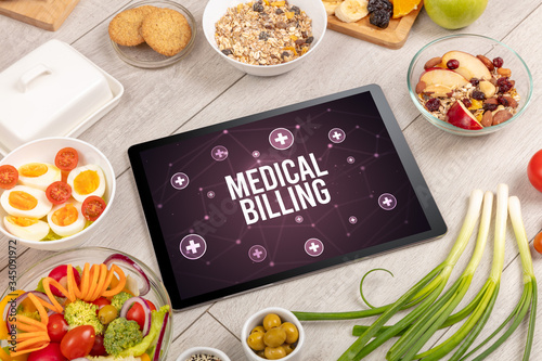 MEDICAL BILLING concept in tablet pc with healthy food around, top view