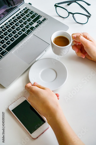 coffee mug, notebook, laptop and female hand on the table on a white background
