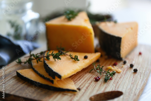 Tasty cheese with thyme and spices on wooden board, closeup photo