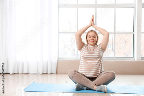 Fototapeta Naklejka Na Ścianę i Meble -  Pregnant woman practicing yoga at home