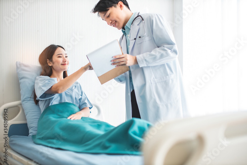  Medicine and health care concept. Asian doctor is taking care patient woman in hospital.doctor or nurse wear protection mask checking and takecare infection people from covid-19 .