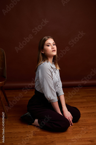 Gorgeous young female in classic suit, black shoes and grey coat. Vintage chair. Woman's clothes.