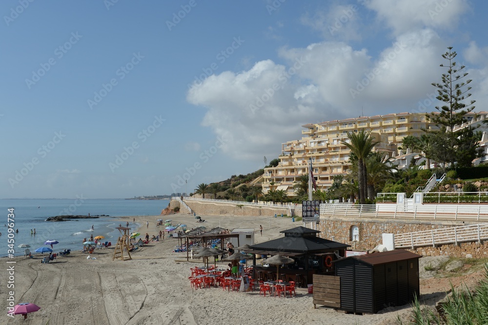 People relax on the sandy beach of Playa de Aguamarina, province of Alicante, Spain
