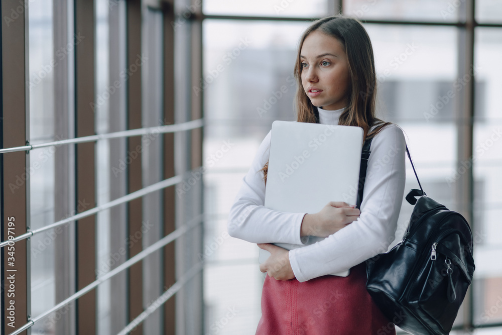 attractive girl walks in a bright corridor with laptop and things in airport terminal or office. travel atmosphere or alternative work atmosphere. freelancer student travels to business meeting. attractive girl walks in a bright corridor with laptop and things in airport terminal or office. travel atmosphere or alternative work atmosphere. freelancer student travels to business meeting.