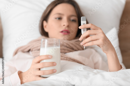 Young woman ill with flu drinking milk in bed
