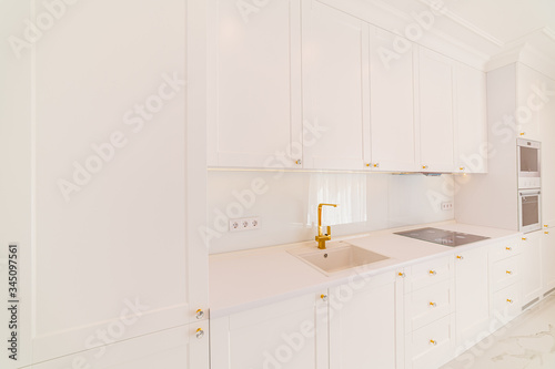 Studio kitchen with white facade in a modern design. LED room lighting. Bright walls with bright curtains. Interior design work
