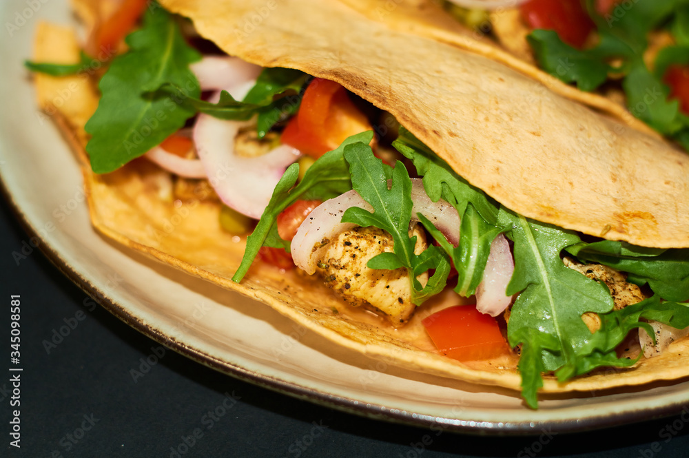 Plate with Mexican cuisine, large tacos with vegetables and meat on black background. Plate with Mexican cuisine, large tacos with vegetables and meat on black background.