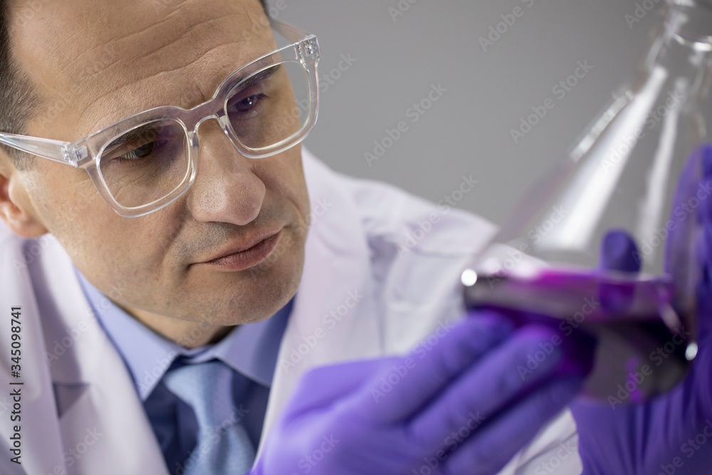Close-up of male scientific chemist synthesizing new compound in clinic research laboratory. Laboratory interior, equipment and lab glassware. Scientific research, experiment and education concept Close-up of male scientific chemist synthesizing new compound in clinic research laboratory. Laboratory interior, equipment and lab glassware. Scientific research, experiment and education concept
