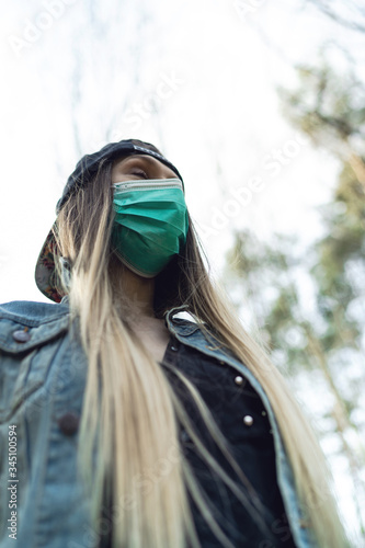 Young Woman Wearing Surgical Mask While Walking in Park. Outdoor and Leisure Activity in Coronavirus Epidemic