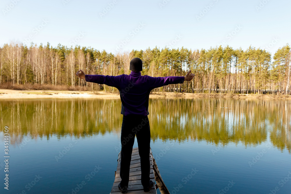 A young man on a bridge by a lake on a sunny day