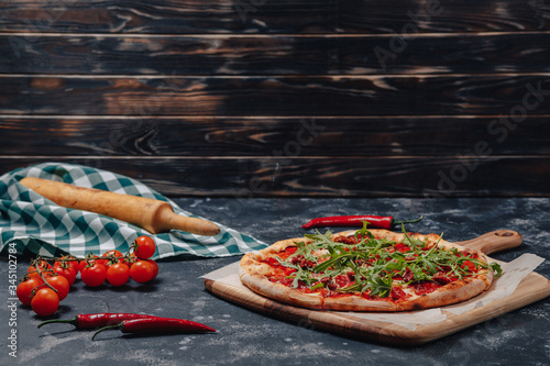 spicy appetizing Neapolitan pizza on board with cherry tomatoes and chilli, free space for text