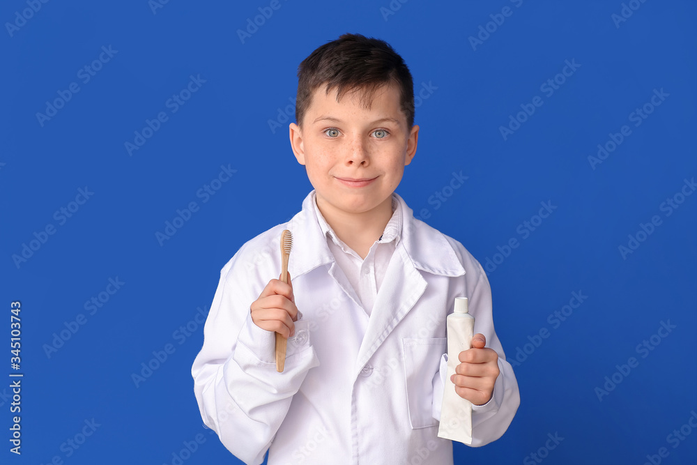 Little dentist with paste and tooth brush on color background
