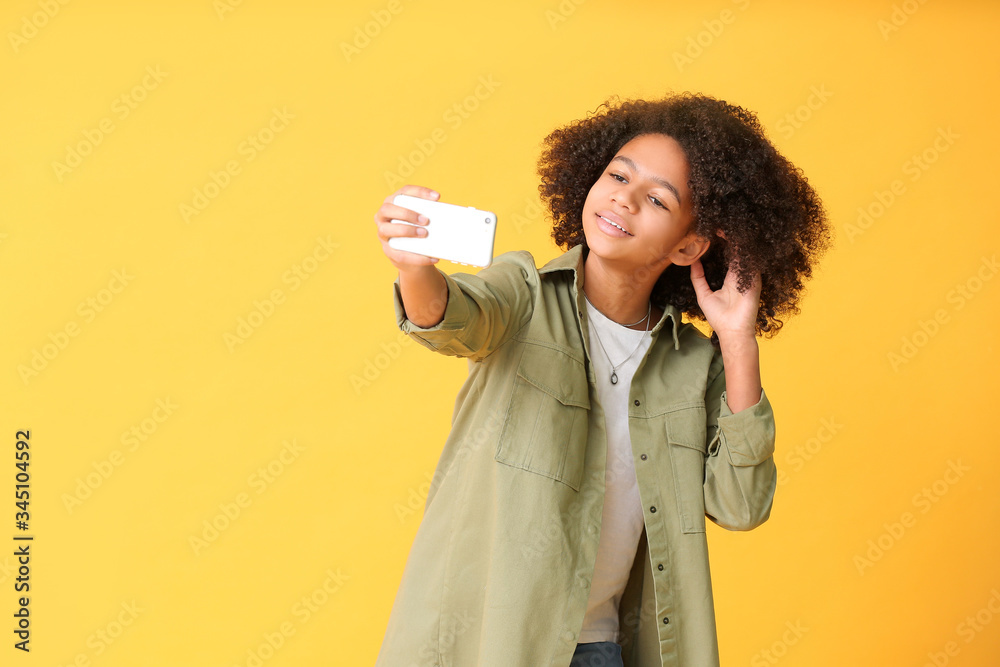 African-American teenage blogger with mobile phone on color background African-American teenage blogger with mobile phone on color background