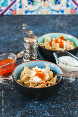 Turkish raviolli in bowls with tomato and yogurt sauces.