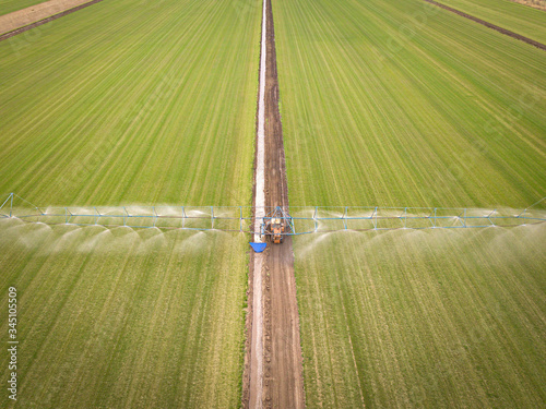 Tractor sprays the field with chemicals. Aerial drone photo.