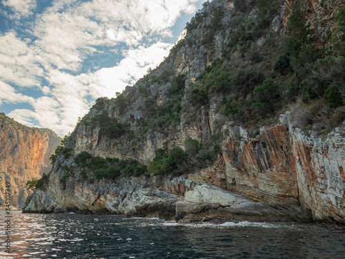 View of the impregnable high rock from below, from the sea. Seashore.