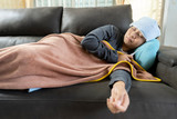 Sick Flu Headache Asian Woman lying on sofa and check temperature by Thermometer.