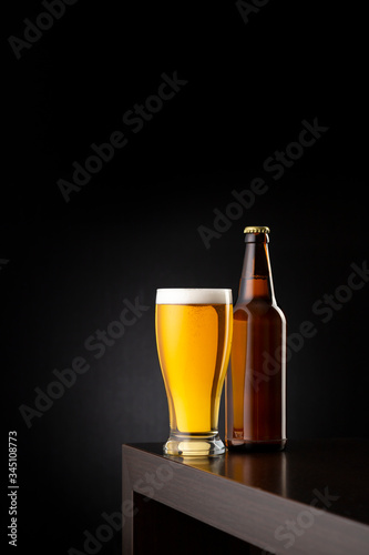 Glass of cold beer and a beer bottle on bar counter