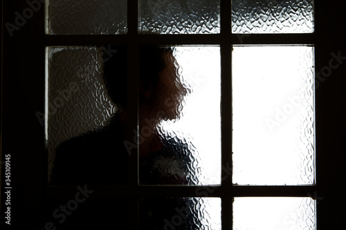 A photograph of a persons profile taken through a blurry door glass