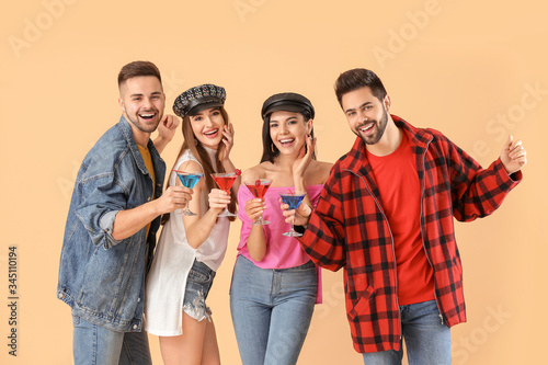 Happy young people with cocktails on color background