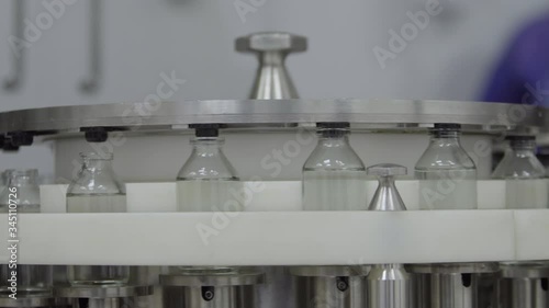 glass bottles filled and sealed with rubber caps on a medical solution conveyor line close up medical industry
