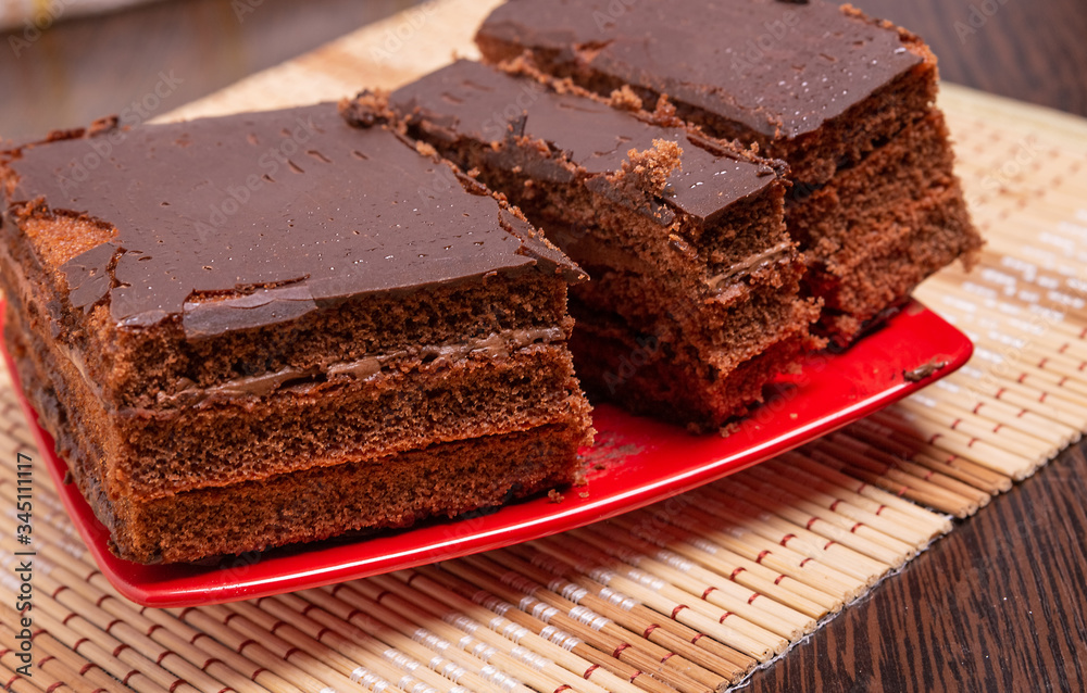 Sliced chocolate cake on a plate on the table. Close up. Sliced chocolate cake on a plate on the table. Close up.