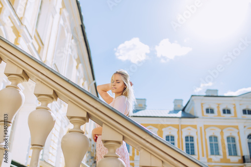 Portrait of beautiful girl in the beautiful palace in summer.  Pretty young woman with pink dress on holiday. © Arta Sermule